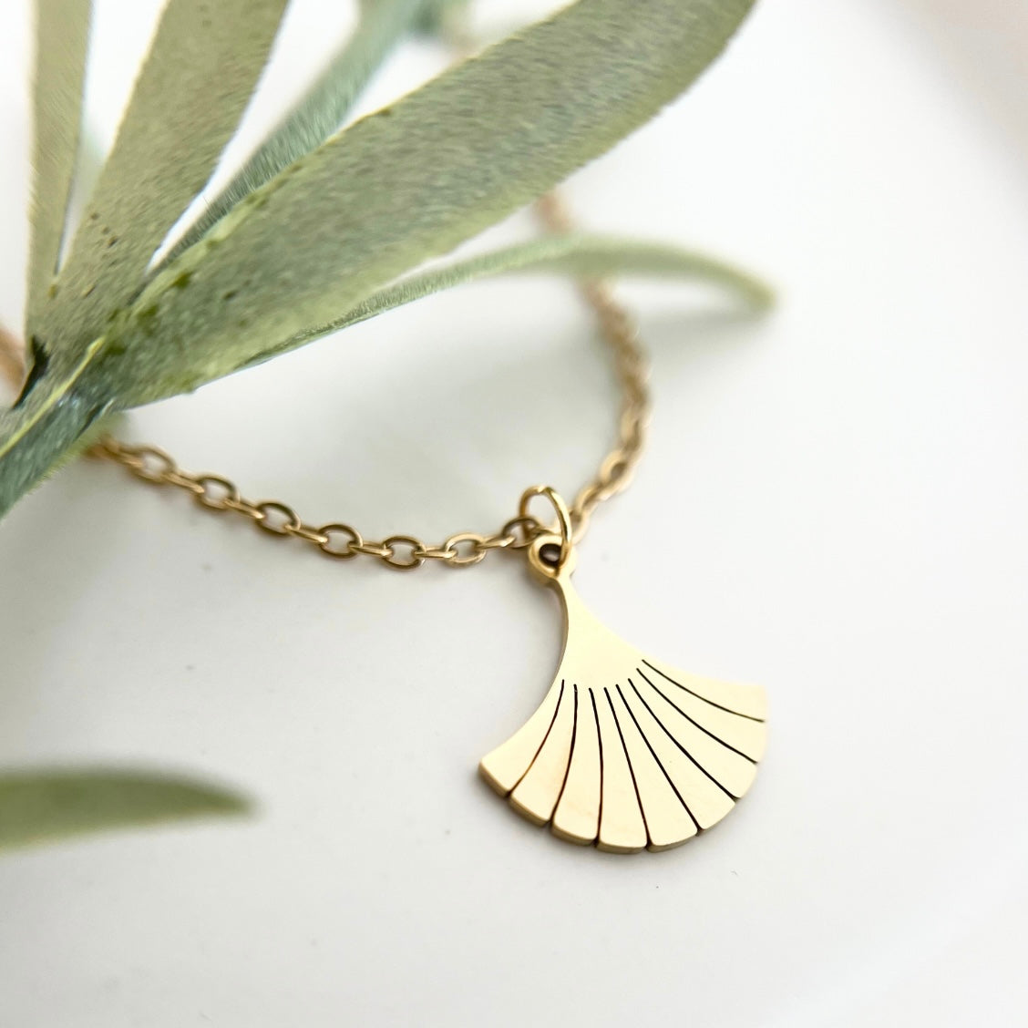 Nahaufnahme der goldenen Edelstahlkette DEIA mit einem filigranen Ginkgo-Blatt Anhänger, der für Stärke und Langlebigkeit steht.