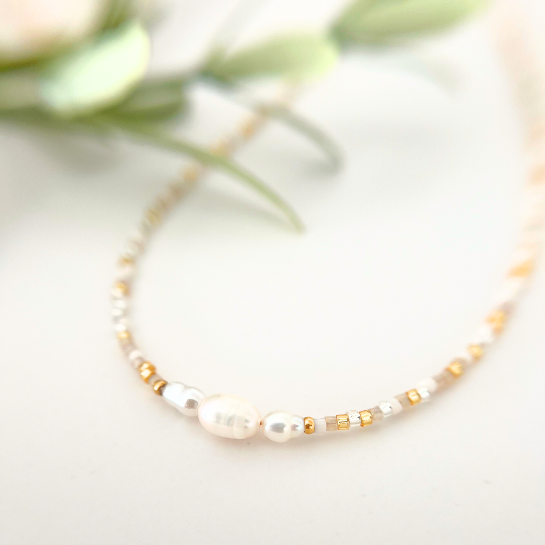Nahaufnahme einer zarten Halskette mit weißen Süßwasserperlen, goldenen Miyuki Rocailles und transparenten Glasperlen – handgemachter Perlenschmuck aus dem Kreativ Perlen Workshop in Wuppertal, perfekt für JGA's und als kreative Mama Auszeit
