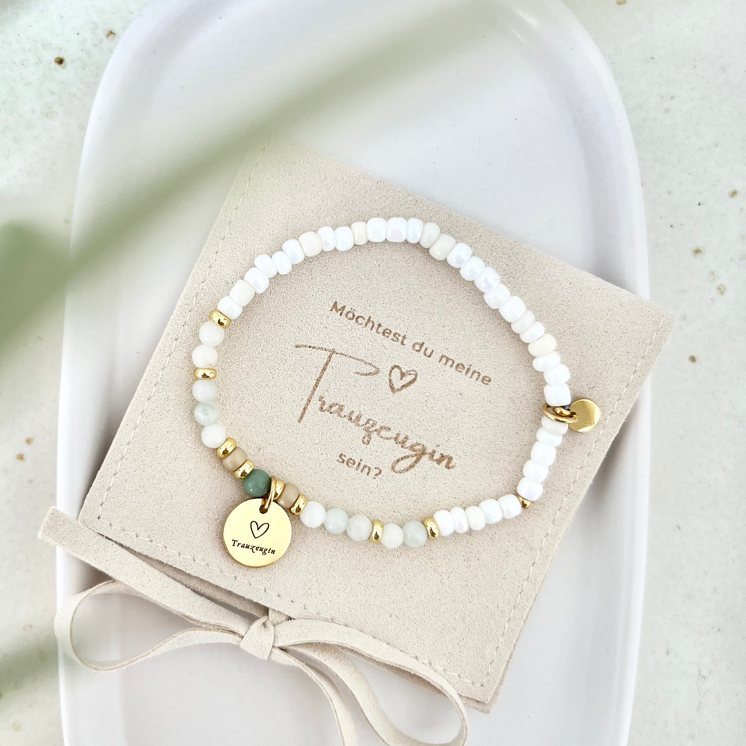 Handgemachtes Armband aus weißen Perlen mit goldenen Akzenten, grünem Detail und graviertem Anhänger „Trauzeugin“, auf beigem Schmuckkärtchen mit der Aufschrift „Möchtest du meine Trauzeugin sein?“