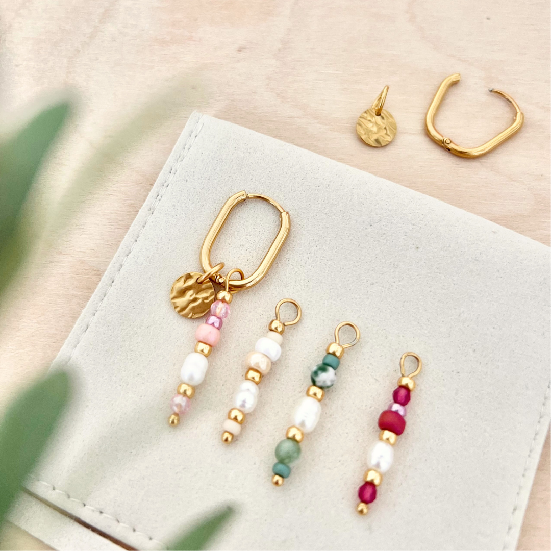 Goldene Creole mit austauschbaren Perlenanhängern in verschiedenen Farben auf Schmuckbeutel, Schmuckset mit Varianten in Grün, Rosa und Weiß