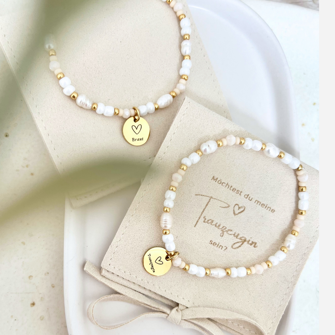 Detailaufnahme eines handgefertigten Perlenarmbands mit Gravuranhänger „Trauzeugin“ – weiße Süßwasserperlen, vergoldete Zwischenelemente und zart beige Miyuki Perlen auf einer weichen Schmuckverpackung, ideal als Geschenk zum Trauzeugin fragen