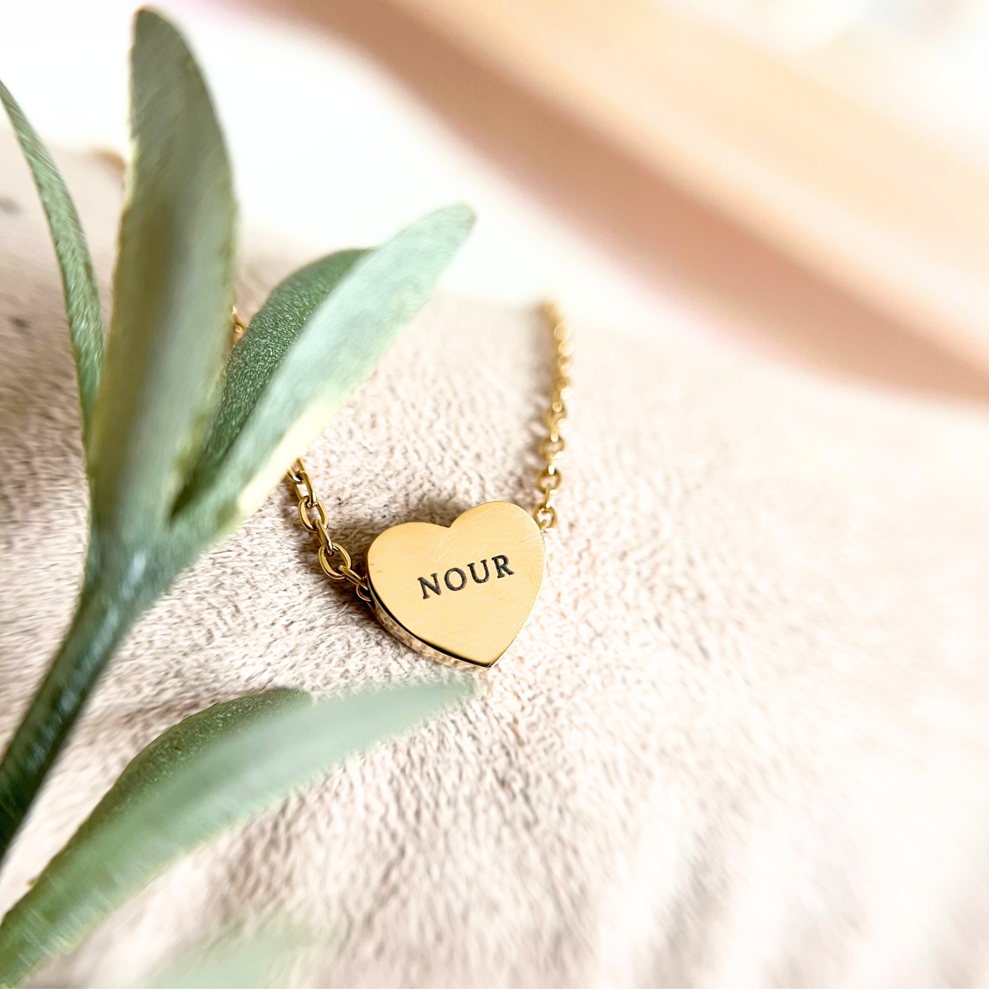 Makroaufnahme einer personalisierten Herz Halskette aus Edelstahl mit Namensgravur auf goldenem Herzanhänger