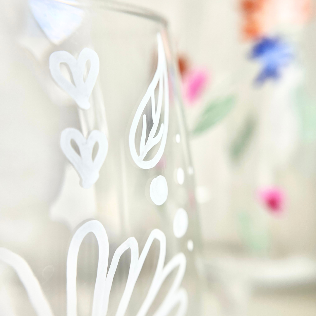 Nahaufnahme eines handbemalten Weinglases mit weißen Linienmotiven: Herzen, Blatt und Punkte – feine Glasmalerei aus dem Kreativ Workshop in Wuppertal, ideal für kreative Gestaltungsideen mit Schablonen oder freihändig - ideal geeignet für einen Mädelsabend