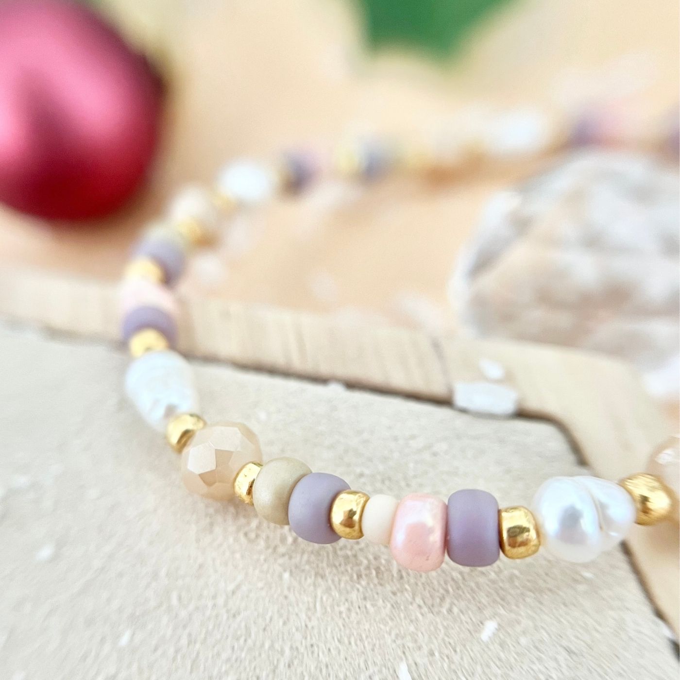 Nahaufnahme der Perlen in verschiedenen Größen – Rosa, Flieder, Beige und Weiß – mit goldenen Zwischenelementen, auf heller Unterlage fotografiert.