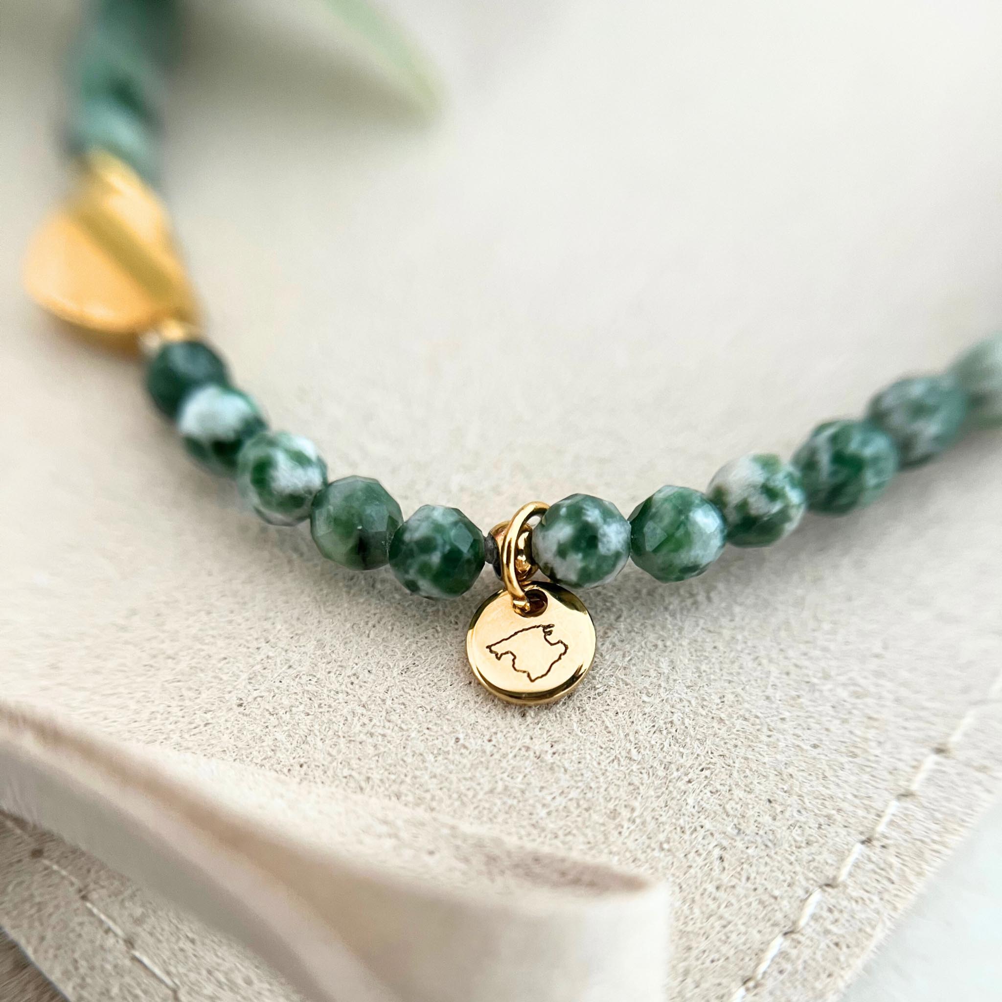 Nahaufnahme des goldenen Gravur-Anhängers des Armbands GENUA, verziert mit marmorierten Natursteinperlen und einem Herzanhänger