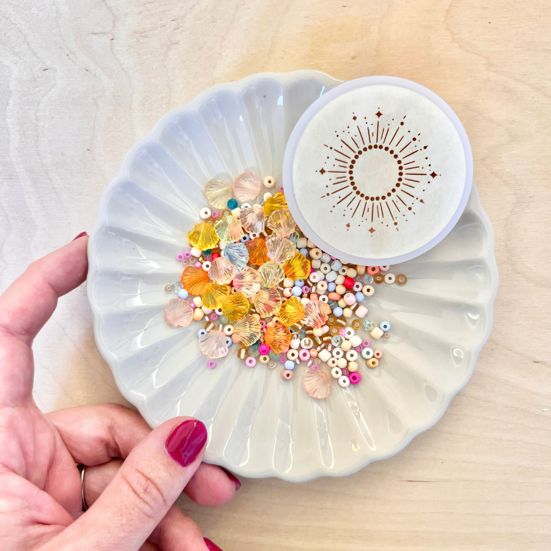 DIY Kinder Bastelset mit bunten Perlen in verschiedenen Größen und Farben, Muschelperlen und goldenen Akzenten in einer dekorativen Schale