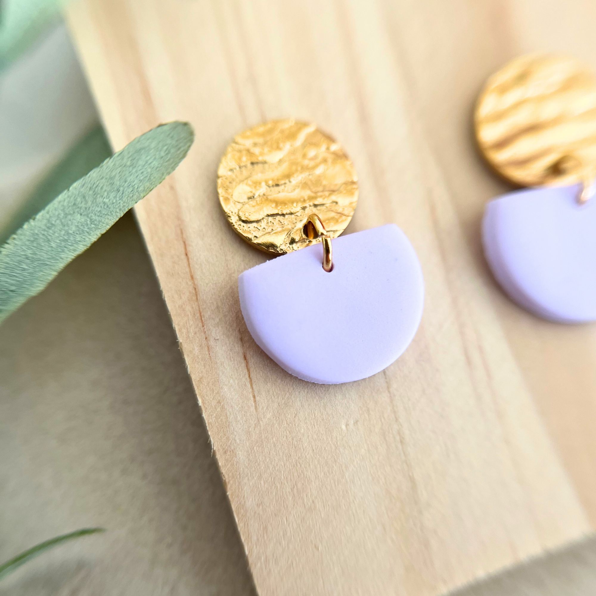 Nahaufnahme eines goldfarbenen Ohrrings ALMERIA aus Edelstahl mit zartem Polymer Clay in Pastellfarbe für ein elegantes und minimalistisches Design