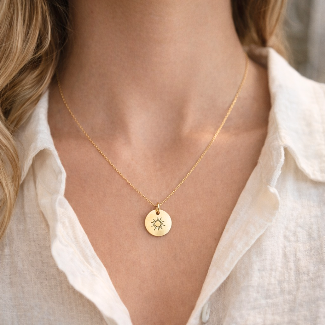 Frau trägt eine filigrane goldene Halskette mit rundem Sonnenanhänger auf der Haut, passend als alltagstauglicher Schmuck oder stilvolles Sommer-Accessoire