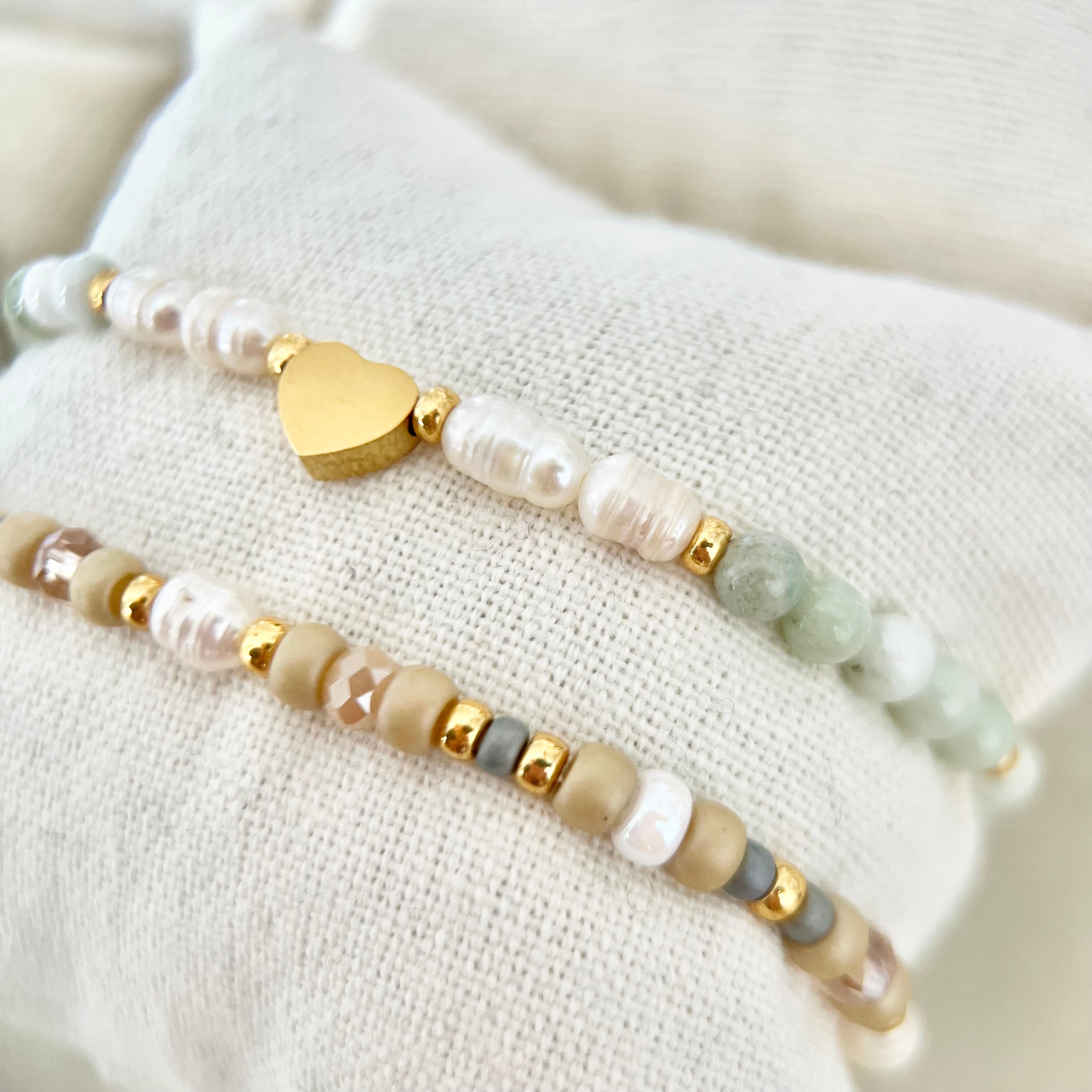 Detailaufnahme der Armbänder mit schimmernden Perlen und Natursteinen, ruhige Farbwelt in Pastell – Sinnbild für Nähe und Wärme.