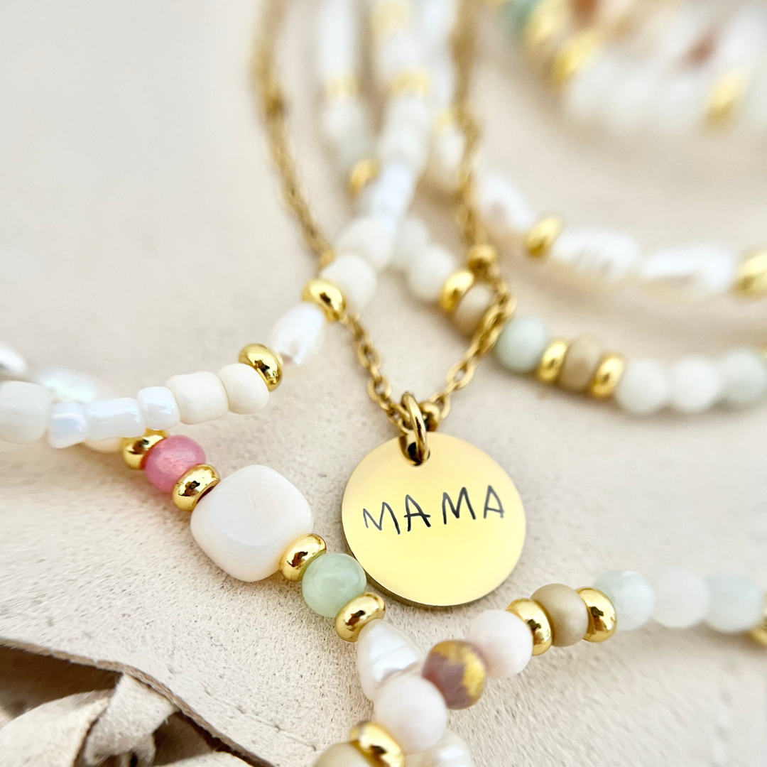 Zarte goldene Kette mit Gravur „MAMA“ in Kombination mit perlmuttfarbenen und pastelligen Perlen – ein liebevolles Schmuckstück als Geschenk für Mütter.