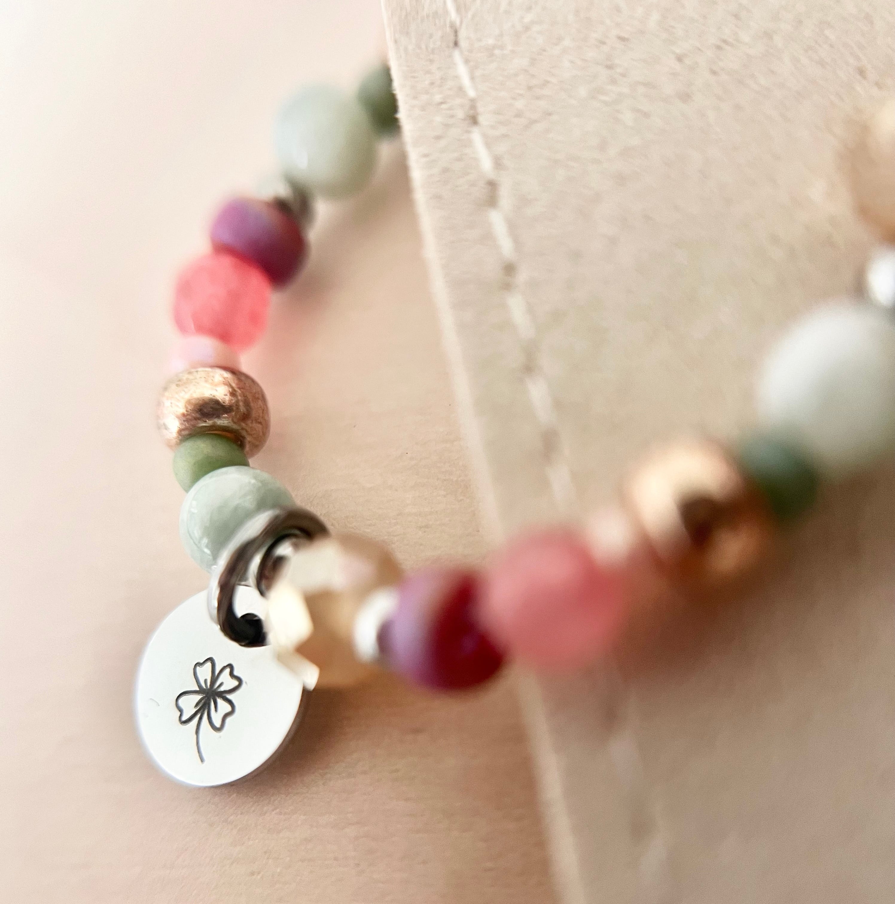 Detailaufnahme des Armbands FELICIA mit rosa, mintgrünen und roségoldfarbenen Naturstein- und Glasperlen sowie silberfarbenem Edelstahl-Anhänger mit Kleeblatt-Gravur.