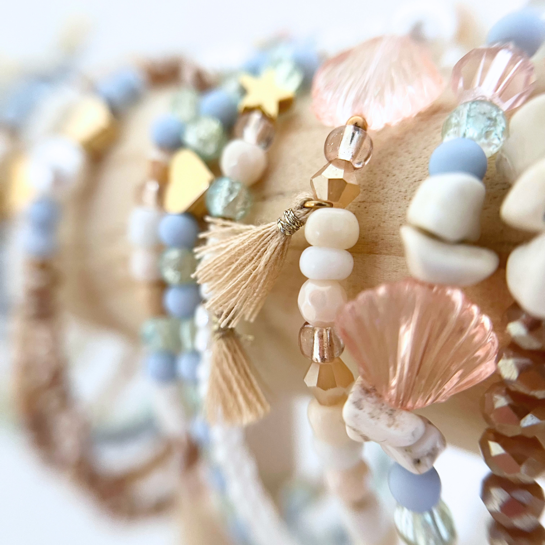 Mehrere handgemachte Armbänder aus dem DIY Kit auf Holz – das perfekte Armband Bastelset für kreative Momente.