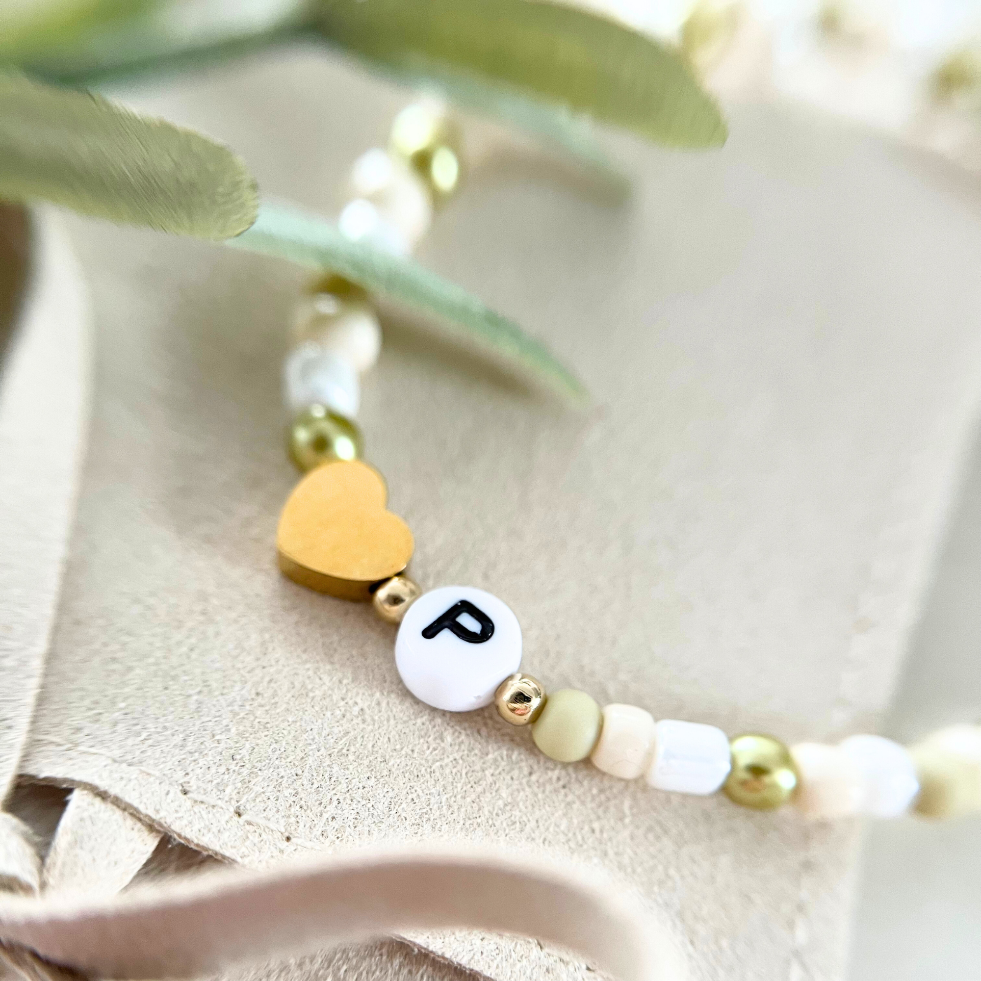 Handgemachtes Armband aus dem DIY Kit VERDE mit goldenem Herzanhänger und einem Anhänger mit dem Buchstaben „P“. Perfekt für personalisierte Geschenke oder als kreatives Armband für Junggesellinnenabschiede.