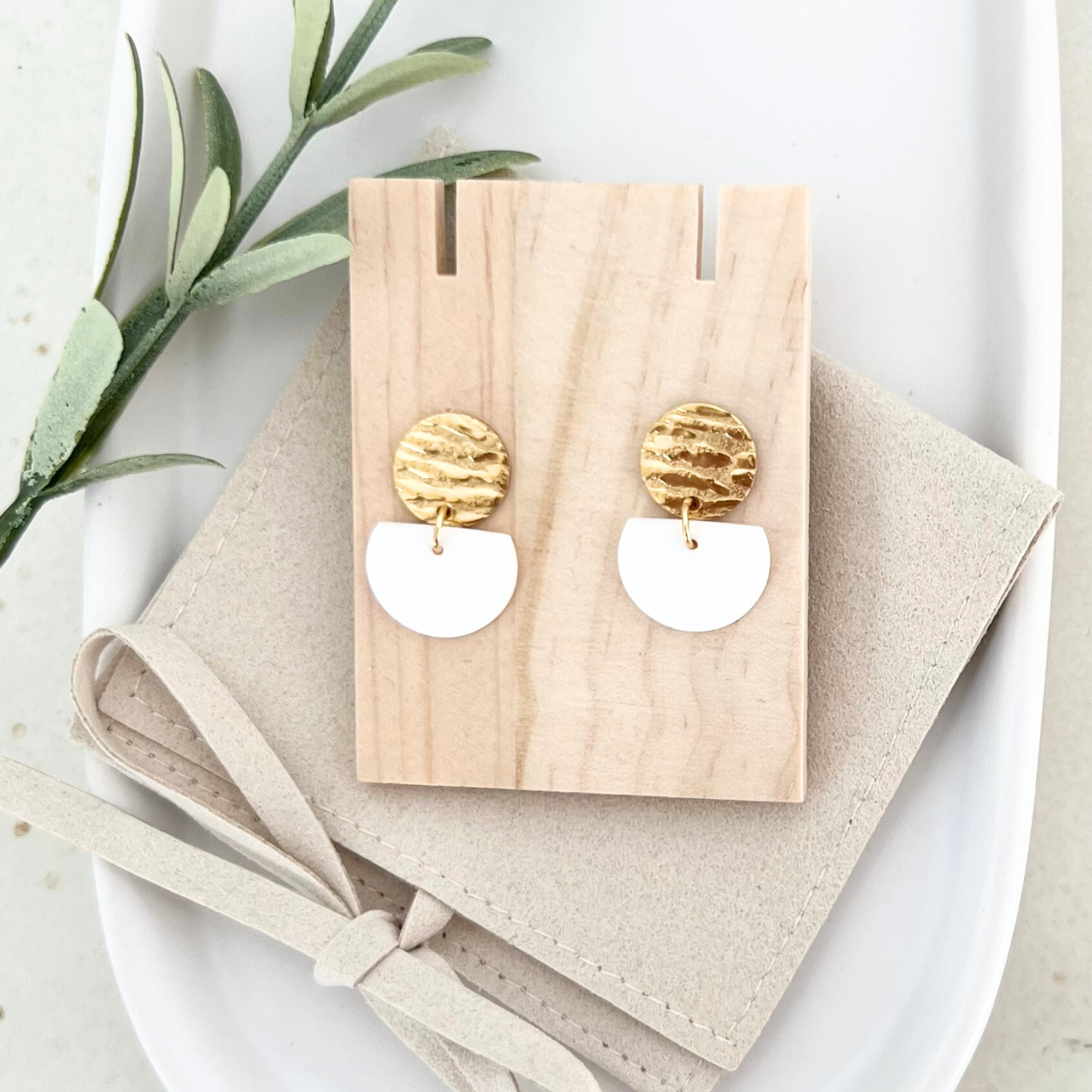 Vollansicht der weißen Ohrringe MURADA auf Holz, die minimalistischen und eleganten Edelstahl-Details betonen