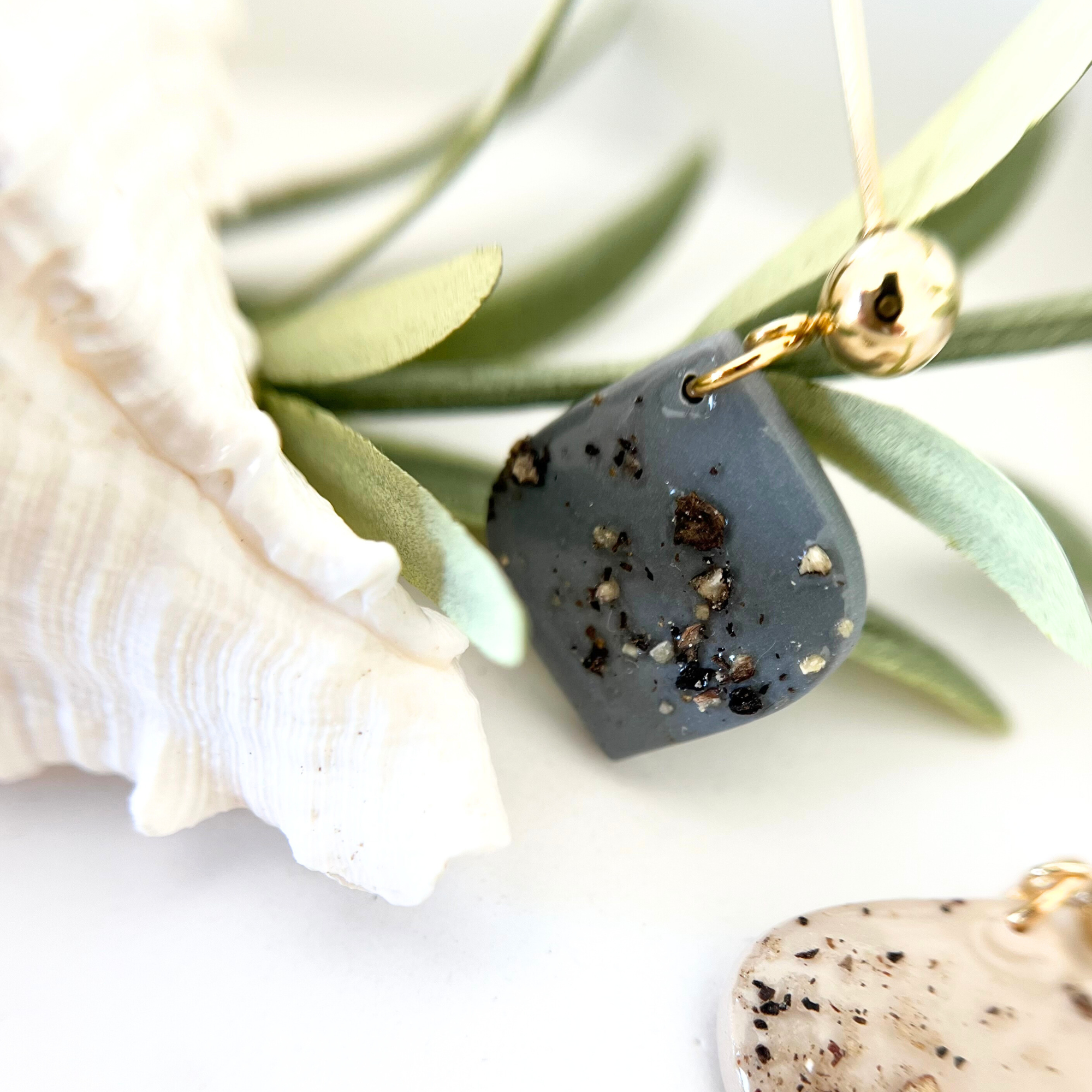 Nahaufnahme eines Ohrrings PIMIENTA mit Muschel im Anschnitt, das außergewöhnliche Design mit Polymer Clay und mallorquinischen Pfefferkörnern