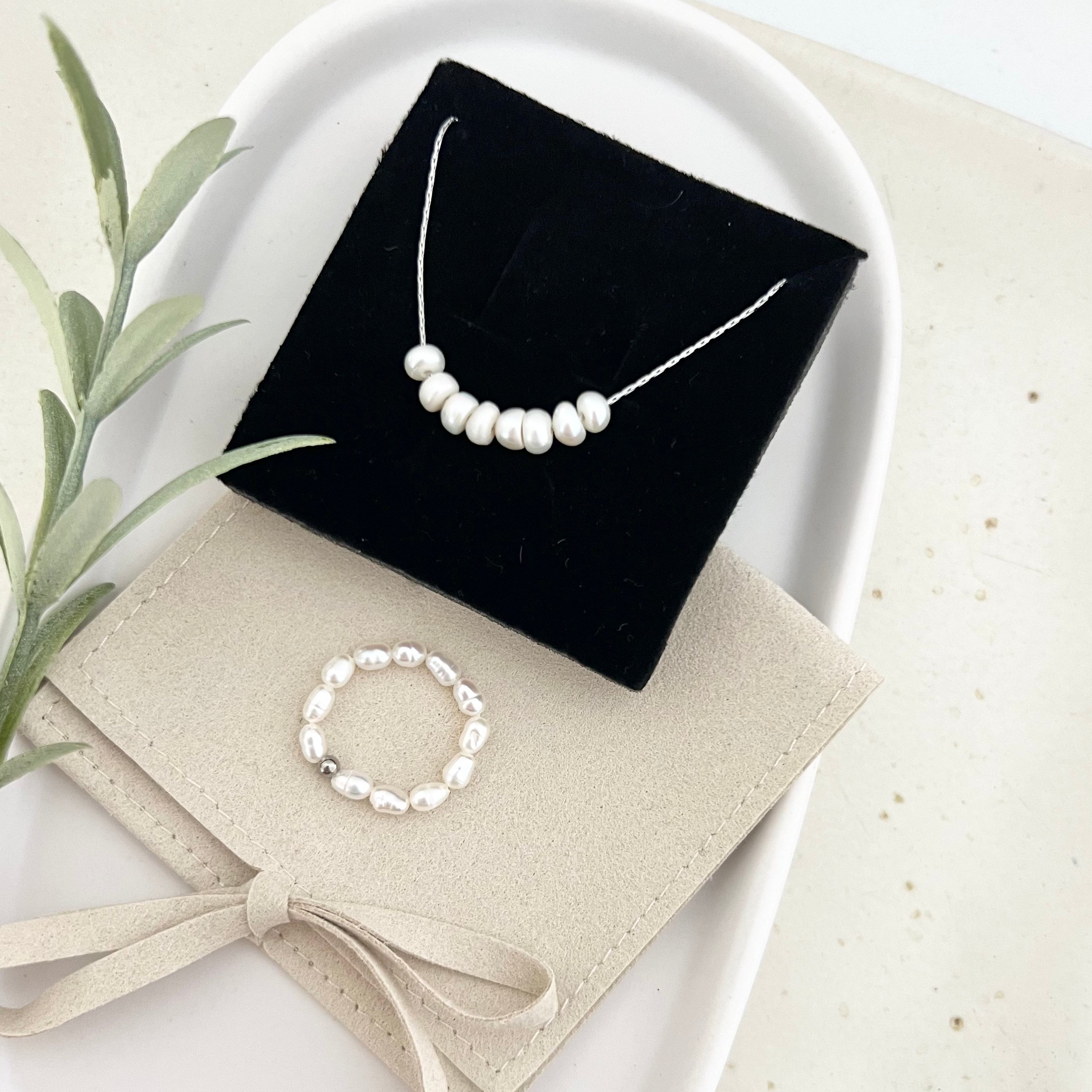 Zeitloses Schmuckset aus einer schlichten Kette mit 8 Süßwasserperlen in der Mitte und einem passenden Perlenring. Das Geschenkset wird gerne an Frauen zum Geburtstag verschenkt.