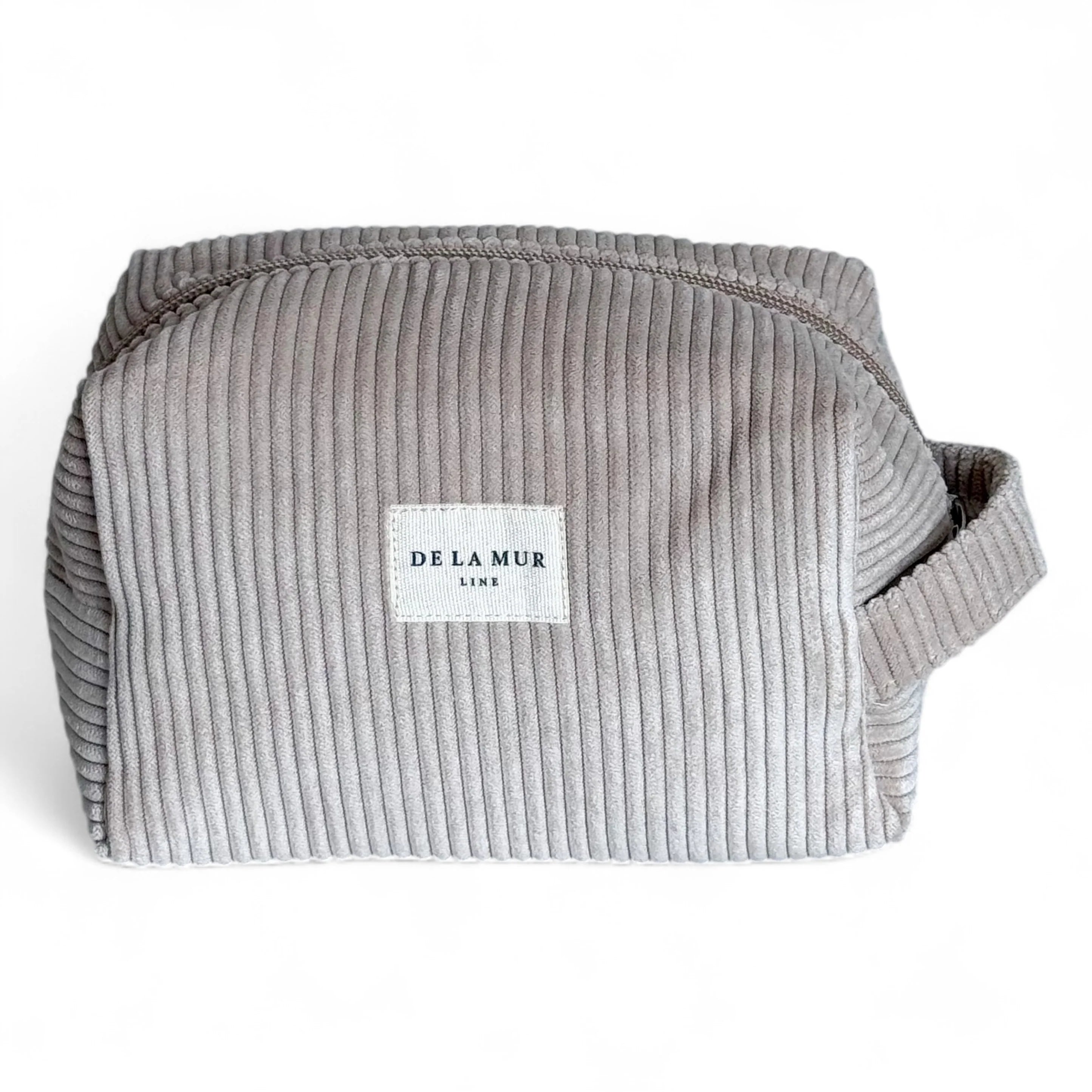 Abgebildet ist eine beige-braune Beauty Bag aus Cordstoff mit Rippenstruktur von DE LA MUR. Die Tasche hat einen seitlichen Griff und eignet sich zur Aufbewahrung von Kosmetik, Pflegeartikeln oder Schmuck – ideal für Reisen oder den Alltag.