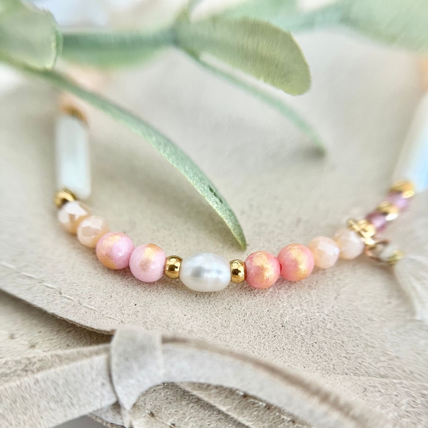 Detailaufnahme des Boho Perlenarmbands "Sommerträume" mit einer anderen Perspektive, die die Süßwasserperle und den Baumwollstoffanhänger zeigt