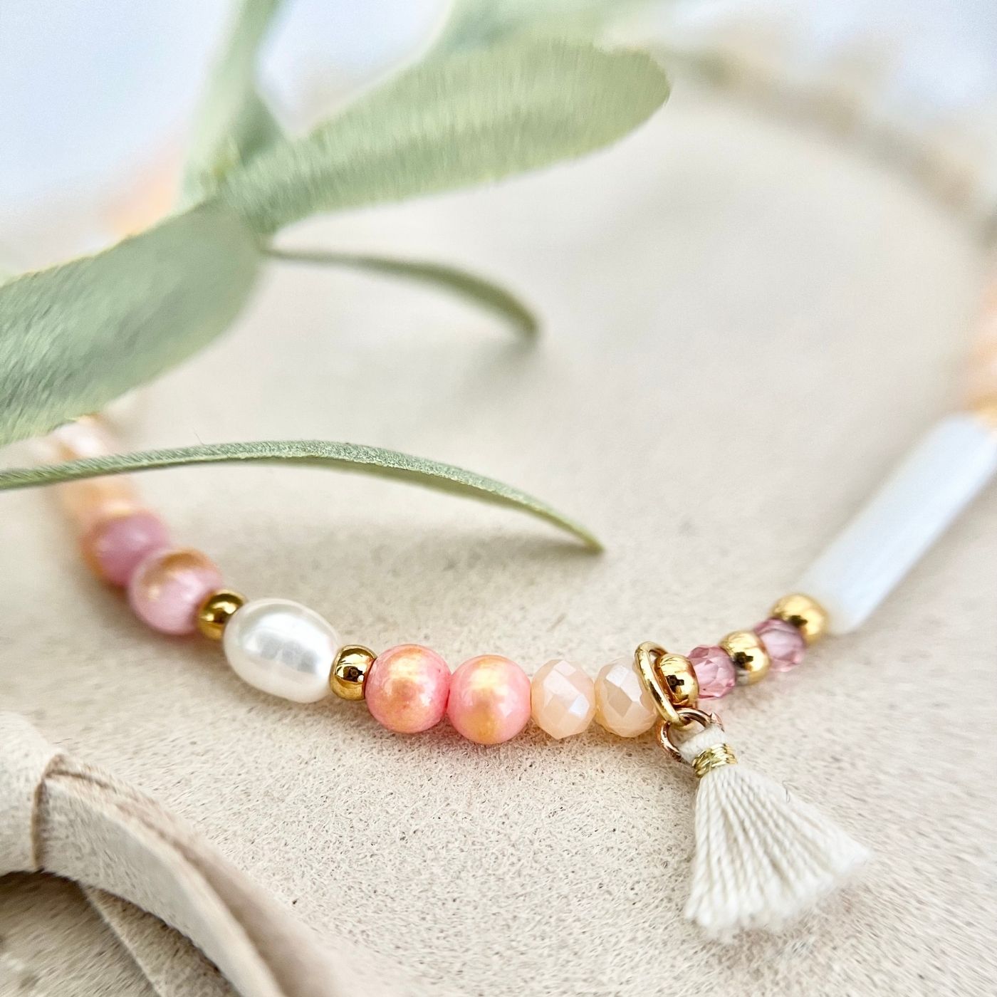 Nahaufnahme des Boho Perlenarmbands "Sommerträume" mit Fokus auf die Süßwasserperle und den verspielten Stoffanhänger aus Baumwolle
