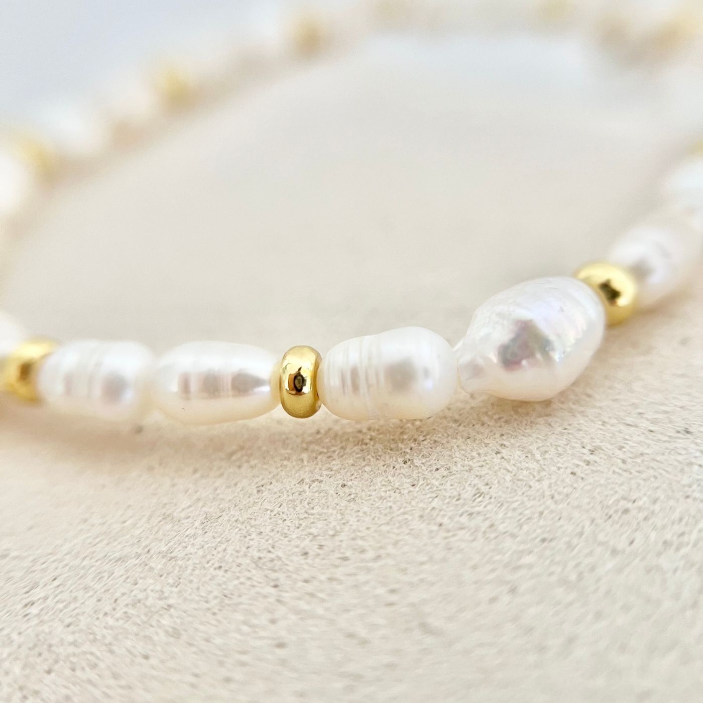 Nahaufnahme des Armbands ALVA, das goldene Edelstahl-Details und eine Süßwasserperle in elegantem Design zeigt