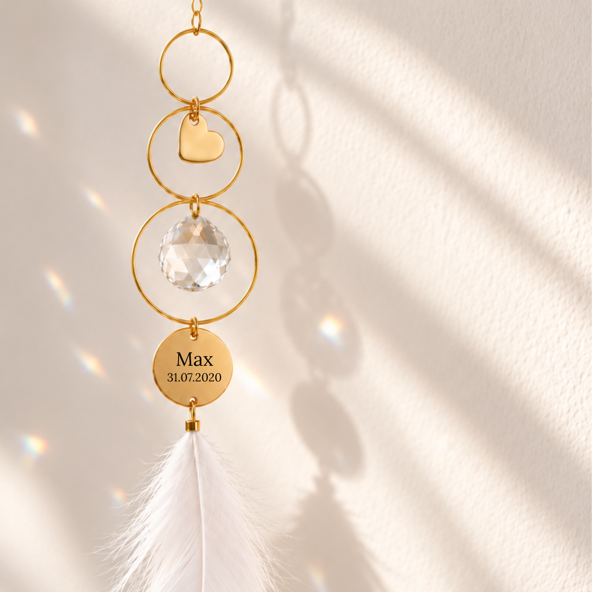 Personalisierter goldener Sonnenfänger mit Herz, Kristallkugel, weißer Feder und Gravur mit dem Namen Max und Geburtsdatum als Geschenk zur Geburt.