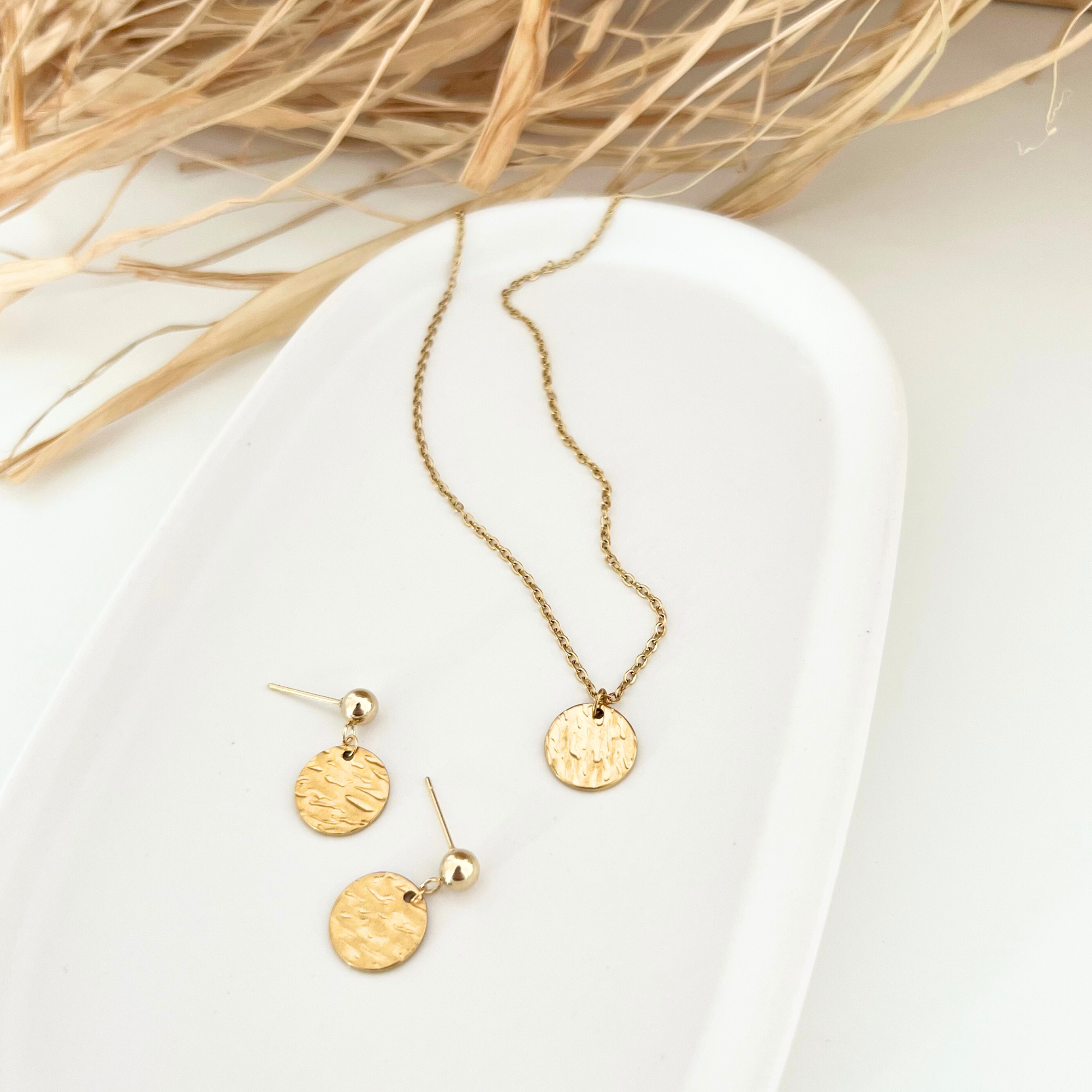 Goldfarbene Edelstahl-Ohrstecker ORO zusammen mit passender goldener Edelstahl-Kette, auf einem Tablet arrangiert