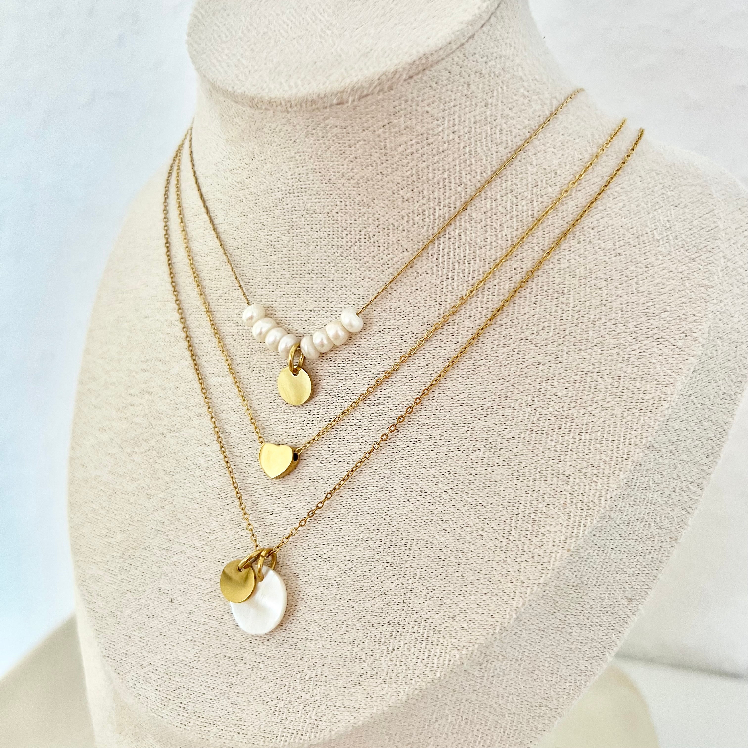 Mehrere Ketten auf Halsattrappe – goldene und silberne Ketten mit Herzanhängern für unterschiedliche Stile