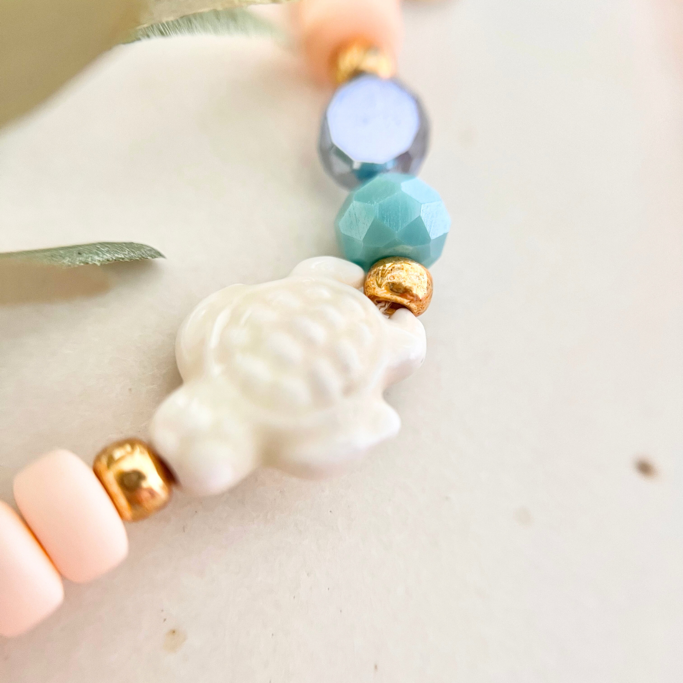 Detailaufnahme einer Natursteinperle kombiniert mit Glasperlen und goldenen Miyuki-Perlen an einer handgemachten Handykette.