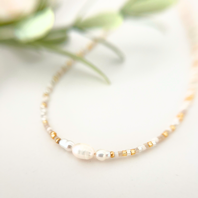 Nahaufnahme einer zarten Halskette mit weißen Süßwasserperlen, goldenen Miyuki Rocailles und transparenten Glasperlen – handgemachter Perlenschmuck aus dem Kreativ Perlen Workshop in Wuppertal, perfekt für JGA's und als kreative Mama Auszeit