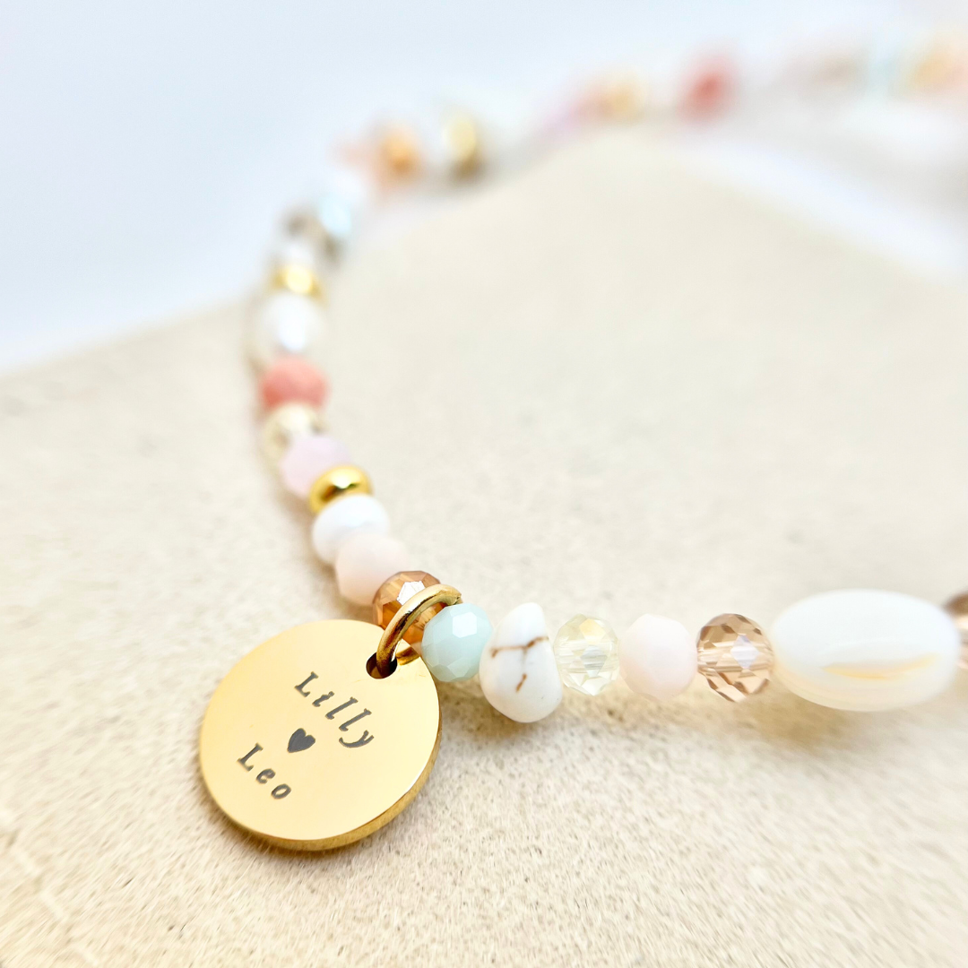personalisiertes Armband aus kleinen bunten Perlen in Pastellfarben mit graviertem Edelstahlanhänger in Gold.  