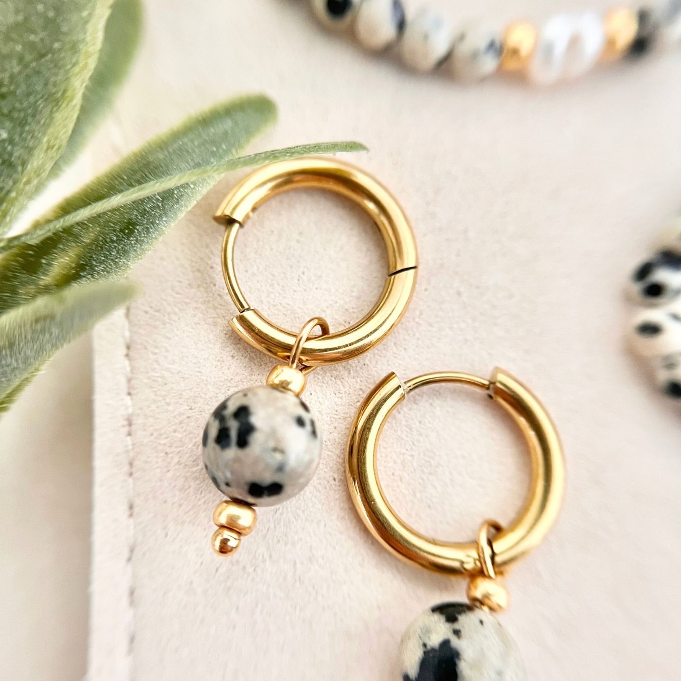 Detailaufnahme der Ohrringe FAYA mit Dalmatiner Jaspis Natursteinperle, individuelle schwarz-graue Marmorierung, hochwertiger Schmuck zum Tragen im Alltag.