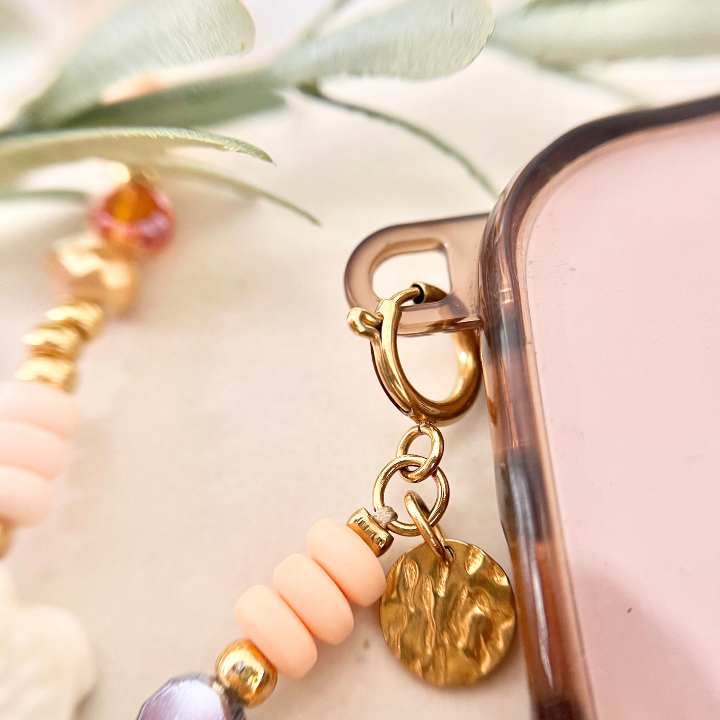 Detailaufnahme der vergoldeten Befestigung einer Handykette mit Perlen und Struktur-Anhänger – hochwertiges Handyband für Handyhüllen mit Ösen.