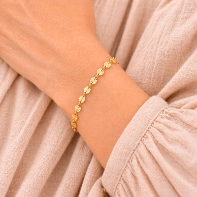 Goldenes Edelstahl Armband mit Sonnen-Elementen am Handgelenk getragen, filigranes wasserfestes Schmuckstück für Damen im sommerlichen Look