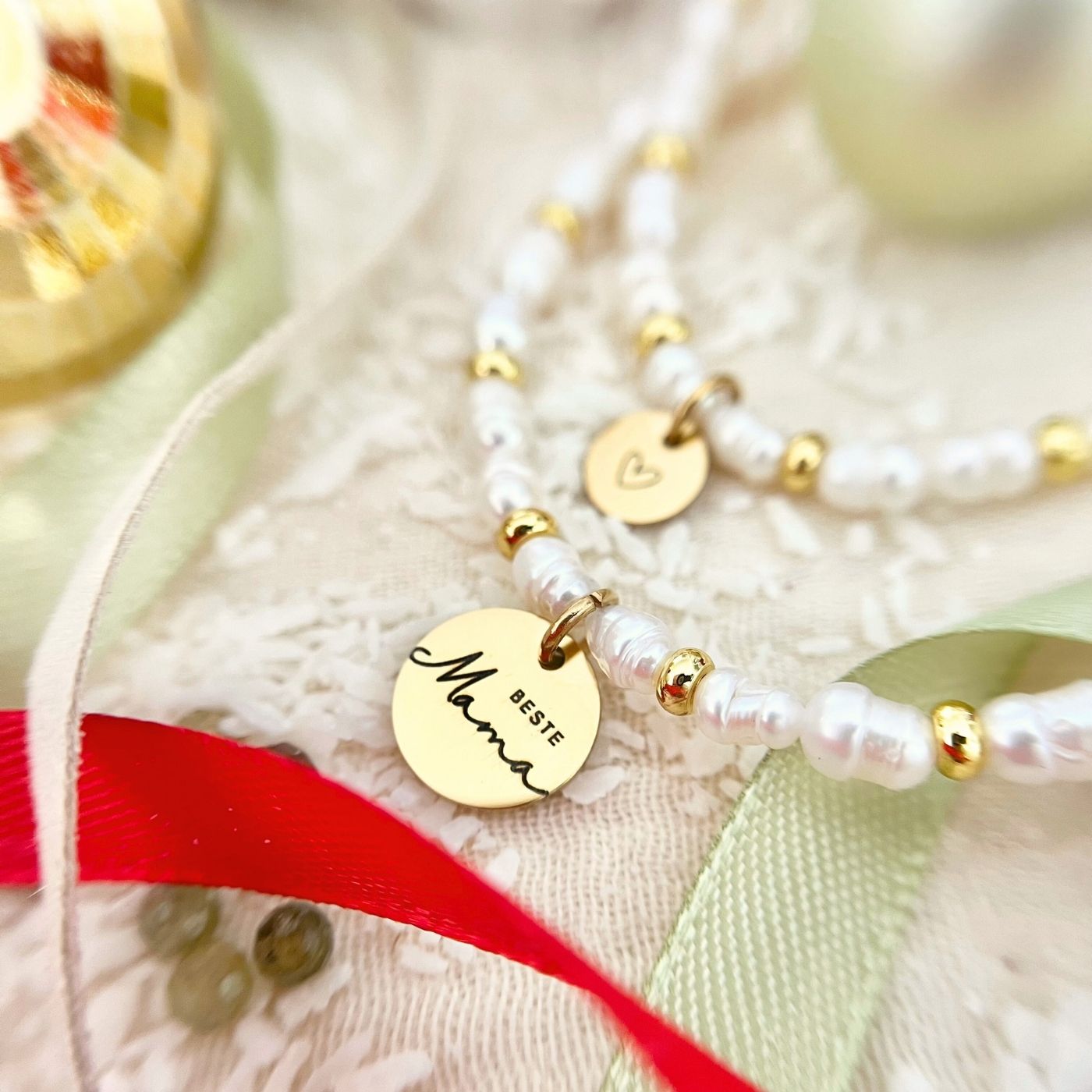 Weihnachtsgeschenk mit rotem Band, weiße Geschenkbox und Perlenarmband aus Süßwasserperlen mit goldenen Elementen als Schmuckidee für Mama.