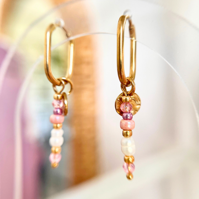 Filigrane goldene Creolen mit Perlenanhängern in Pink und Weiß, Nahaufnahme mit weichem Bokeh-Hintergrund, detailreiches Schmuckbild