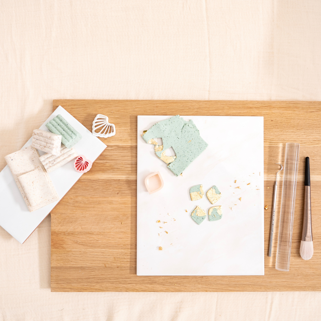 Arbeitsplatz im Polymer Clay Workshop mit Modelliermasse in Beige und Mintgrün, Blattgold, Ausstechern, Acrylroller und Werkzeugen – kreative Vorbereitung zum Schmuck selber machen in Wuppertal, ideal für Anfänger und DIY-Liebhaber