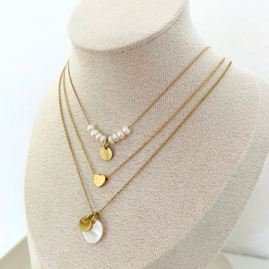 Mehrere Ketten auf Halsattrappe – goldene und silberne Ketten mit Herzanhängern für unterschiedliche Stile