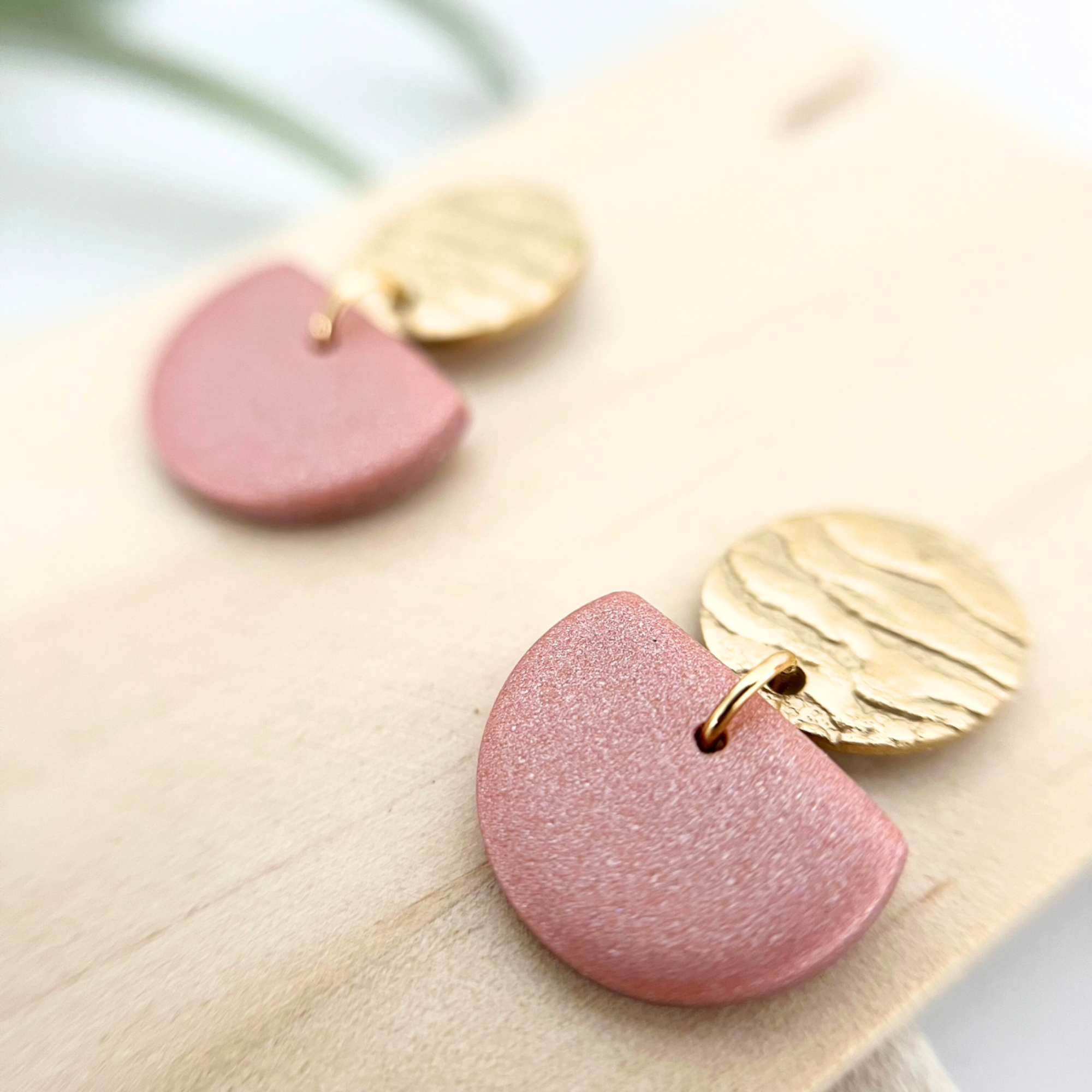 Nahaufnahme eines goldenen Edelstahl-Ohrrings SOL mit gehämmertem Stecker und edlen warmen Farben in Bronze, Beige und Taupe aus Polymer Clay.