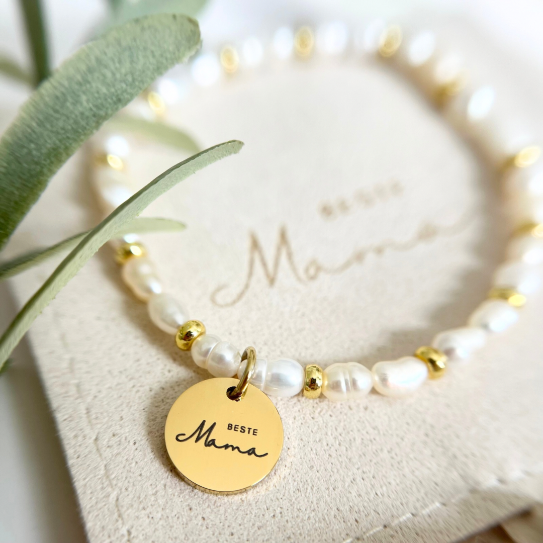 Elegantes Armband aus Süßwasserperlen mit goldenen Details und rundem Edelstahl-Anhänger „Beste Mama“, stilvoll präsentiert auf einer Schmuckverpackung mit Aufschrift „Mama“ – perfektes Geschenk zum Muttertag oder Geburtstag.