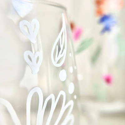 Nahaufnahme eines handbemalten Weinglases mit weißen Linienmotiven: Herzen, Blatt und Punkte – feine Glasmalerei aus dem Kreativ Workshop in Wuppertal, ideal für kreative Gestaltungsideen mit Schablonen oder freihändig - ideal geeignet für einen Mädelsabend