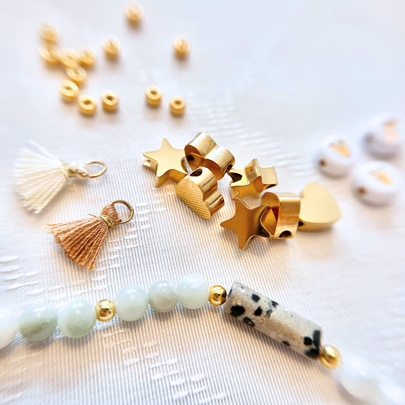 Detailaufnahme aus dem Premium JGA DIY Armband Bastelset mit goldfarbenen Edelstahlperlen in Stern- und Herzform, Boho Quasten Anhängern, Natursteinperlen und wasserfesten Perlen für individuelle Freundschaftsarmbänder und DIY Armbänder beim Junggesellinnenabschied.