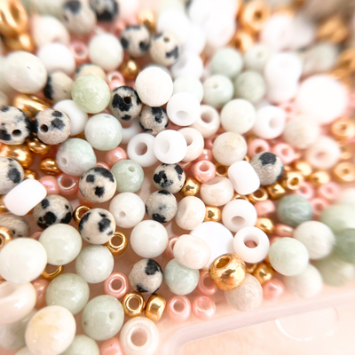 Makroaufnahme von Perlenmix mit Natursteinperlen, weißen Schmuckperlen und goldenen Zwischenperlen für DIY Armband Set