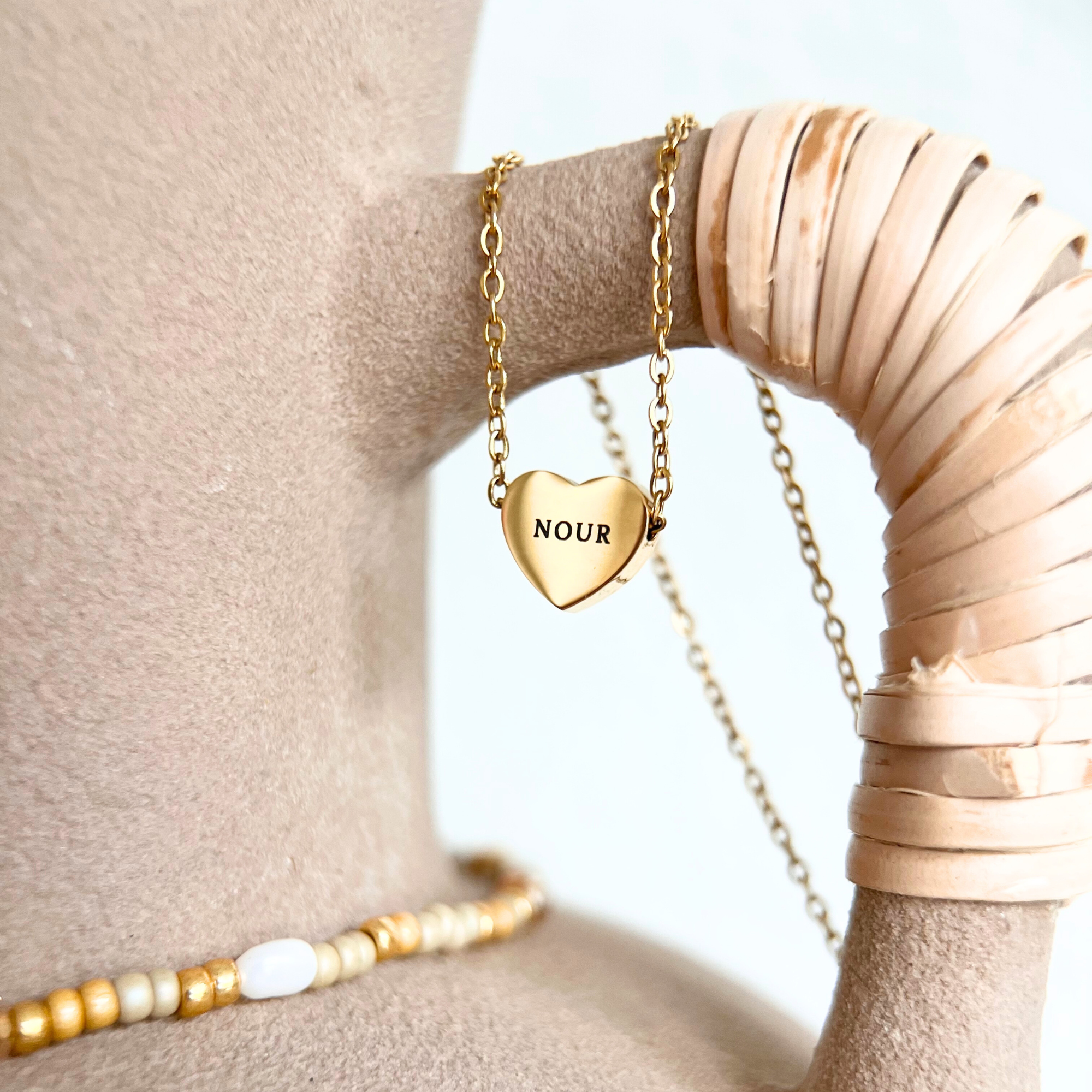 Detailaufnahme einer goldenen Herzkette mit graviertem Namen auf Herzanhänger aus Edelstahl, personalisierte Halskette als Geschenk