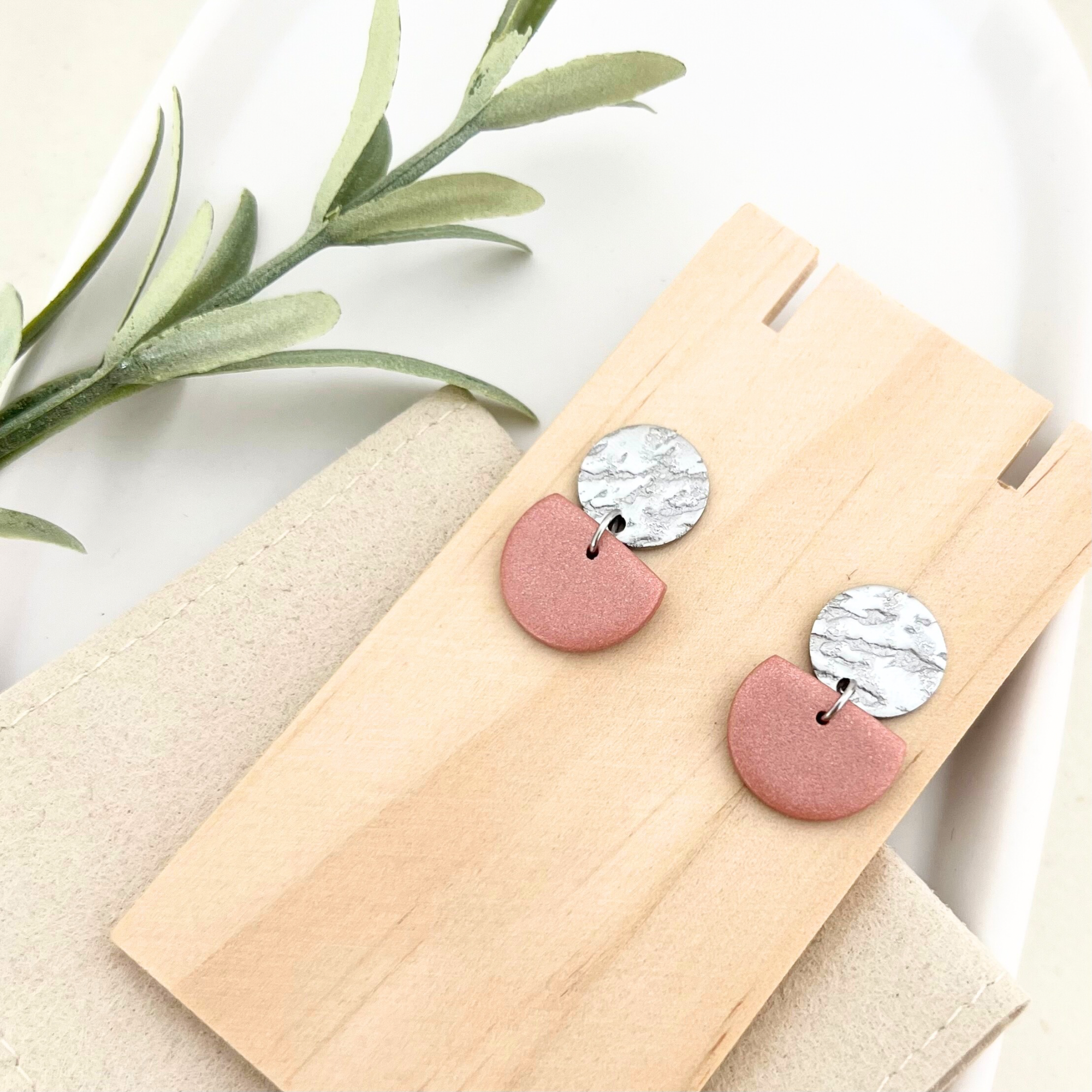Gesamtaufnahme eines Paares silberner Edelstahl-Ohrringe SOL mit gehämmertem Stecker und warmen Farben aus Polymer Clay.