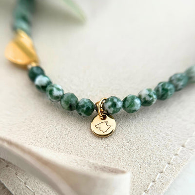 Nahaufnahme des goldenen Gravur-Anhängers des Armbands GENUA, verziert mit marmorierten Natursteinperlen und einem Herzanhänger