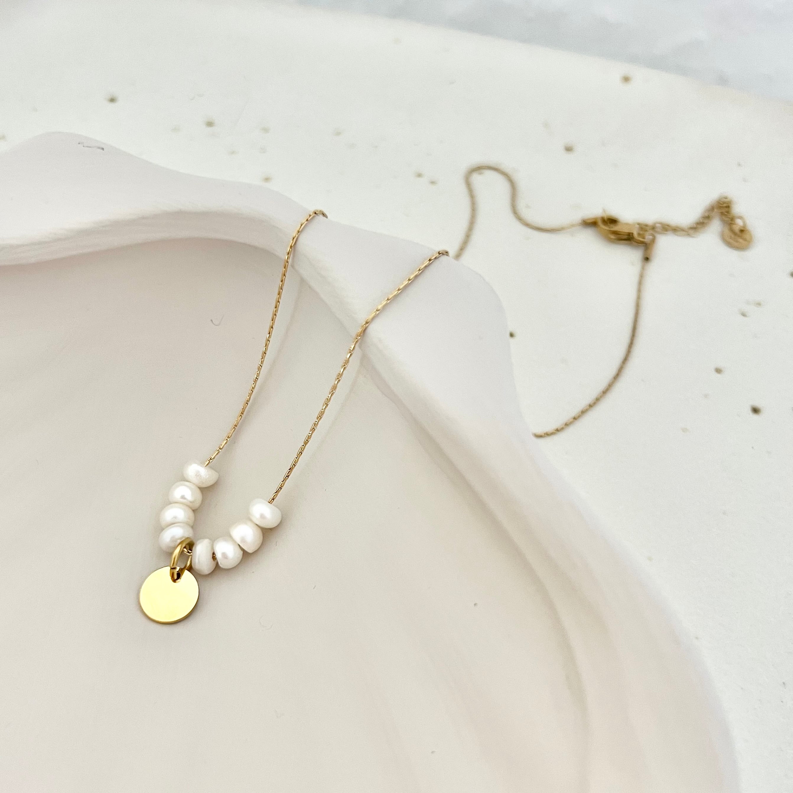 Goldene Kette mit Anhänger und Süßwasserperlen liegend – ein edles Schmuckstück für einen persönlichen Look
