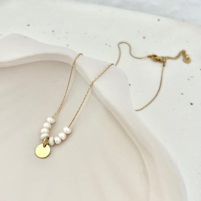 Goldene Kette mit Anhänger und Süßwasserperlen liegend – ein edles Schmuckstück für einen persönlichen Look