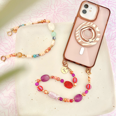 Gesamtansicht einer personalisierten Handykette mit bunten Perlen, Keramik-Fisch und graviertem Namensanhänger neben einem Smartphone – dekoratives Handyband für Handyhüllen mit Ösen.