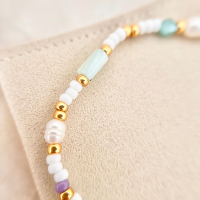 Detailbild vom Perlenmix aus weißen Miyuki-Perlen, goldenen Elementen und länglicher türkisfarbener Perle – elastisches Perlenarmband für Frauen