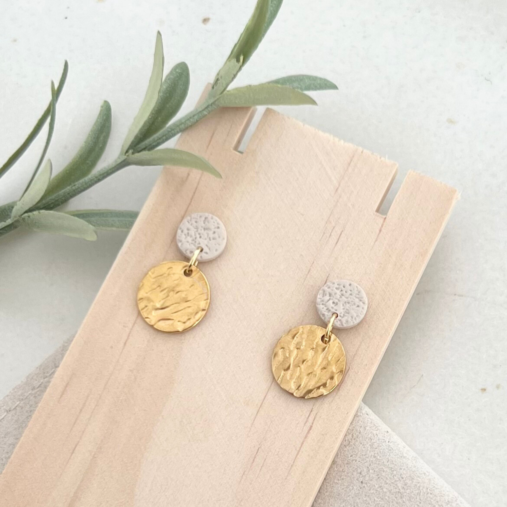 Ohrstecker ALARO aus Edelstahl und Polymer Clay mit gehämmertem Anhänger, auf Holz und goldfarbenem Edelstahl abgebildet